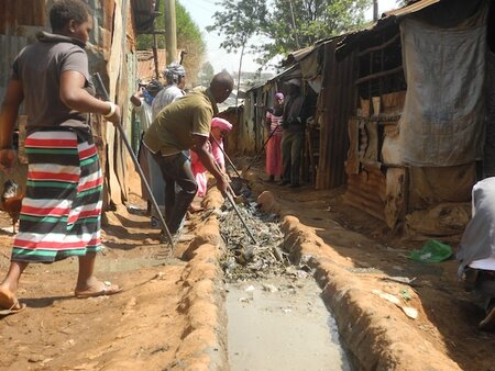 People outside raking solids in a sewage system